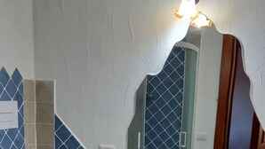 A bathroom with a white sink, two toilets, and a mirror with a light fixture.