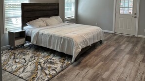 Une chambre à coucher avec un lit, une table de chevet, un ventilateur de plafond et une porte.