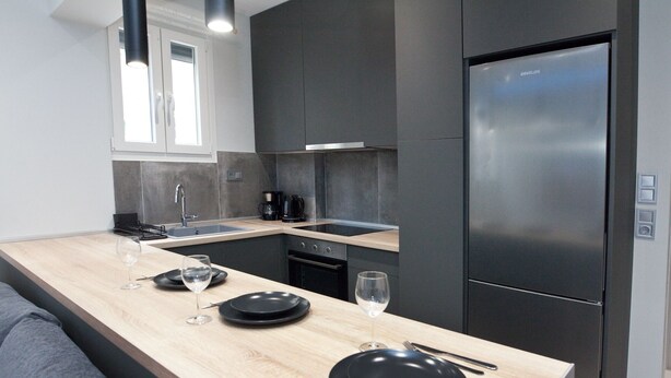 A modern kitchen with a built-in stove, sink, and a large refrigerator.