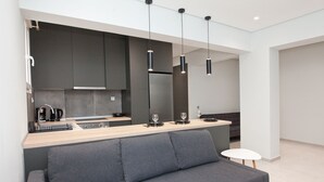 A modern kitchen with dark cabinets, a wooden countertop, and a grey sofa.