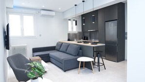 A modern kitchen with a grey sofa, a small dining table, and a plant.