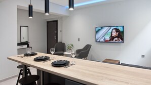 A modern dining area with a long wooden table, black chairs, and pendant lighting.