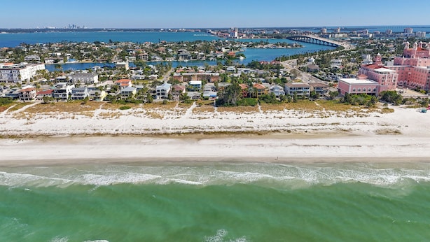 Une vue aérienne d’une ville côtière, avec des propriétés situées en bord de mer, une marina et un pont reliant les différents quartiers.