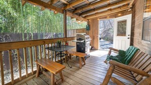 An outdoor deck with wooden benches and a grill. - Cozy Cabin w/ Hot Tub & Fenced in Yard for Pets (Hot Springs)