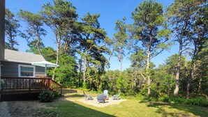 Un jardin avec une terrasse en bois, du mobilier d’extérieur et une pelouse.
