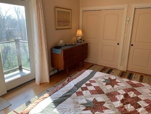 Ein Schlafzimmer mit einem großen Bett, einem Schminktisch, einem Schreibtisch und einem Fenster mit Blick auf Bäume.