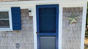 Una casa con puerta azul, decoración de estrella y ventana con contraventanas azules.