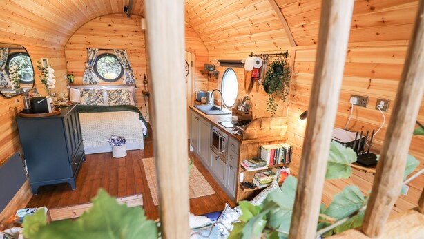 Un intérieur chaleureux et rustique, avec un lit, une petite kitchenette et une salle de bain.