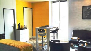 A modern hotel room with a bed, a desk, two chairs, a sofa, and a large window. - Vittel Loc's : Le 214 Classé 3 Osez L'expérience! (Vittel)