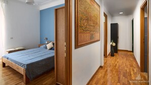 A bedroom with a bed, a nightstand, a wall-mounted lamp, and a large map. - Domus Alberico 11 (Vaticano) (Roma)