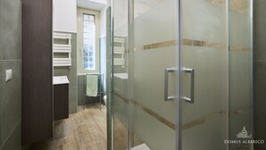 A modern bathroom with a glass shower enclosure, a wooden vanity, and a built-in shelf. - Domus Alberico 11 (Vaticano) (Roma)