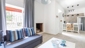 Uma sala de estar moderna com um sofá cinzento, almofadas listradas, uma mesa de centro branca e uma lareira.