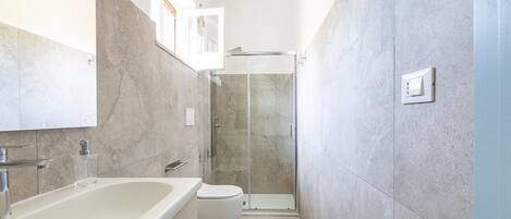 A modern bathroom with a bathtub, toilet, and glass-enclosed shower.