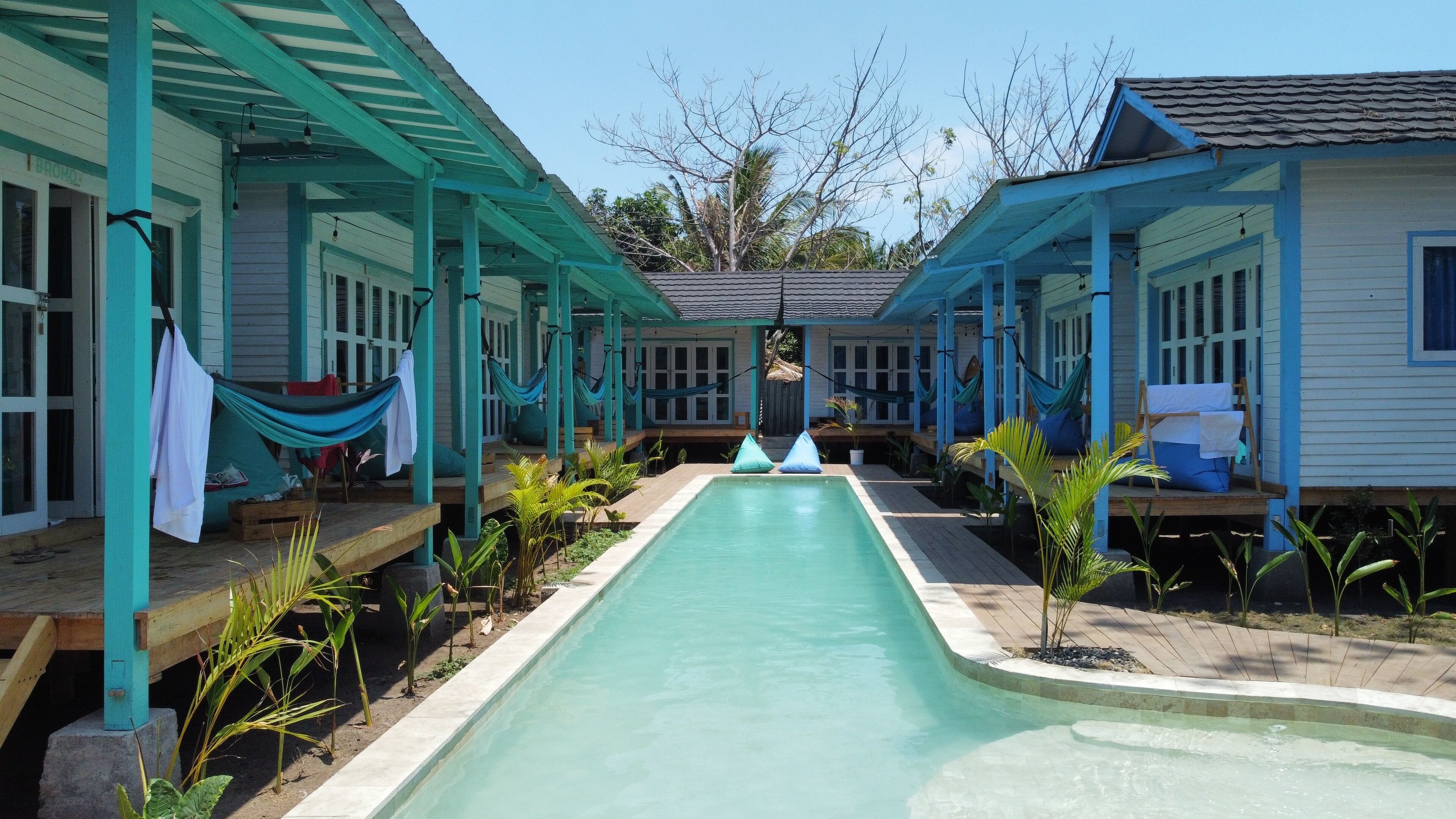Un área de piscina con hamacas y sillas de descanso, rodeada de pequeñas casas con un estilo arquitectónico uniforme.
