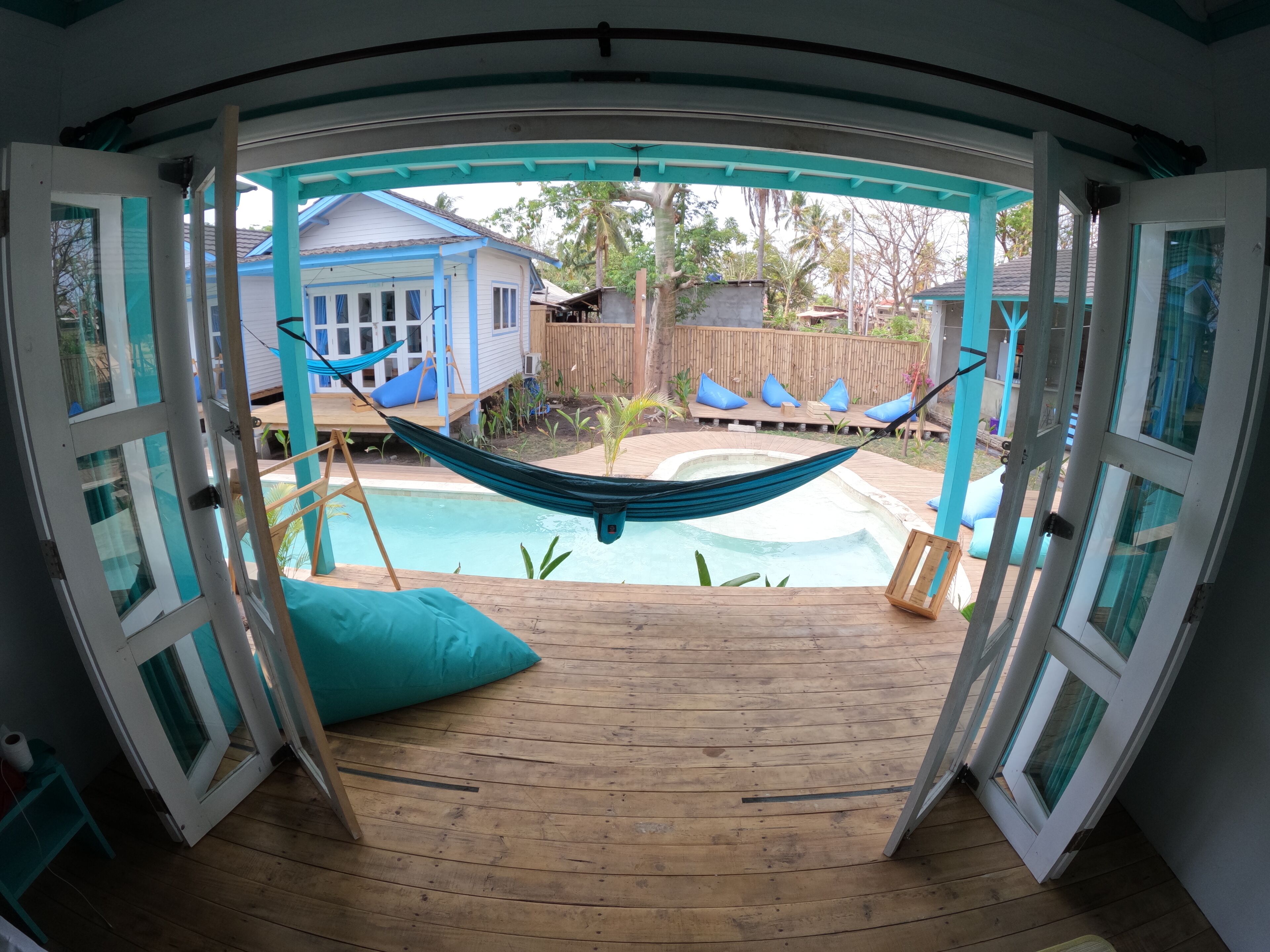 A wooden deck with a hammock and a pool.