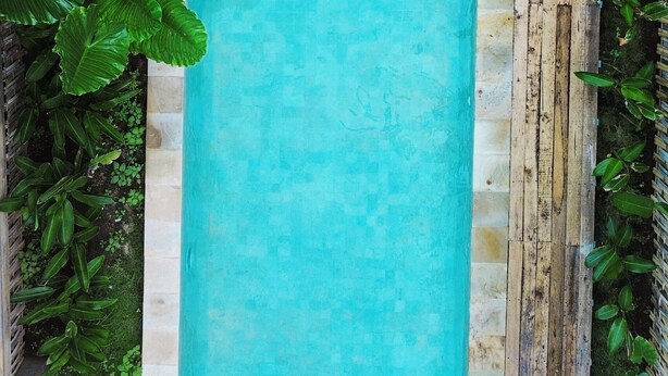 Vista aérea de uma piscina com uma pessoa deitada em um flutuador azul.