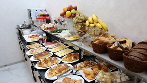 A buffet with various food items including fruits, bread, and pastries. - Saroy Palace Hotel (Qarshi)