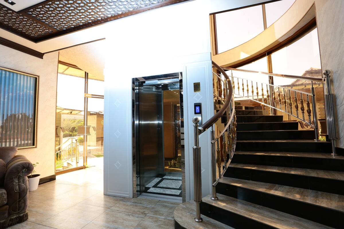 A modern interior with a staircase, an elevator, and a view to the outside.