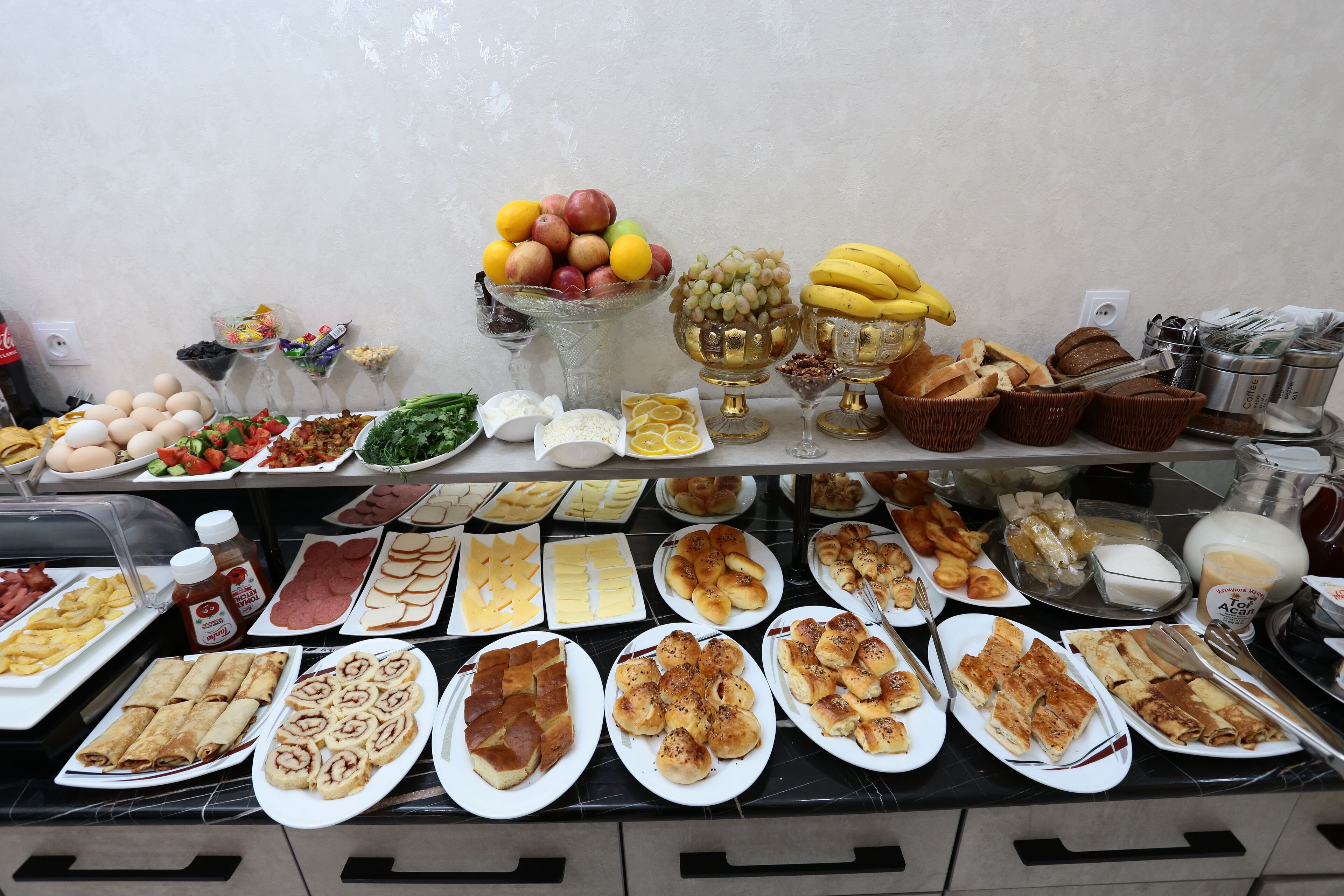 Un buffet con diversi cibi, tra cui frutta, pasticcini e prodotti da colazione.