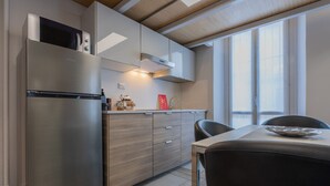 A modern kitchen with a stainless steel refrigerator, wooden cabinets, and a dining area with a table and chairs. - Studio degli Artisti by Wonderful Italy (Torino)