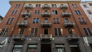 A multi-story building with a brick facade, multiple balconies, and storefronts on the ground floor. - Studio degli Artisti by Wonderful Italy (Torino)
