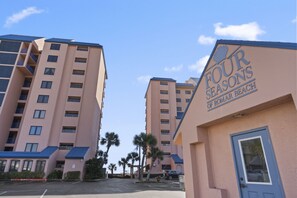 A hotel named 'Four Seasons of Roman Beach' with multiple high-rise buildings, a parking lot, and palm trees. - Four Seasons 604W by Liquid Life (Orange Beach)