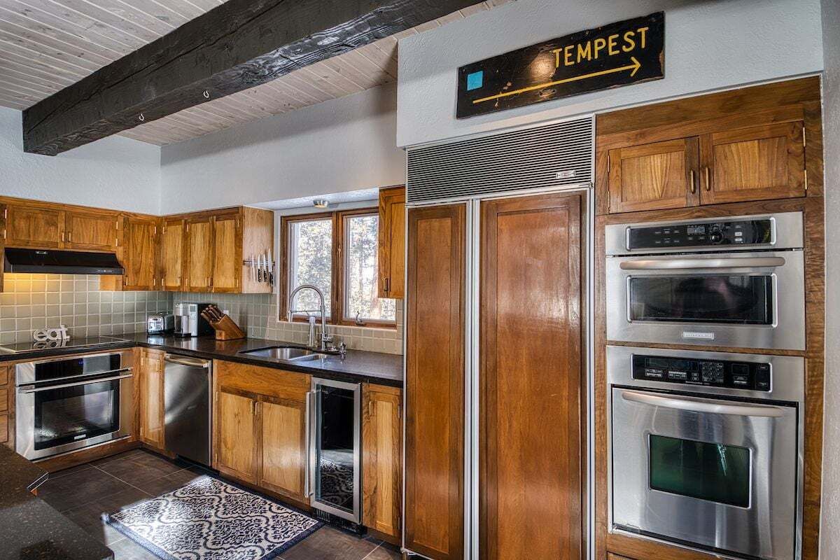 A kitchen with wooden cabinets, stainless steel appliances, and a sign indicating 'TEMPEST'.