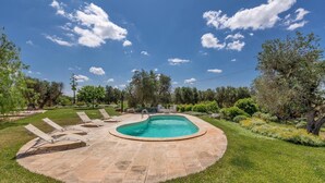 A swimming pool with a stone deck, surrounded by grass and trees. - 3536 Villa Le Majole by Perle di Puglia (Manduria)