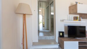 Een moderne woonkamer met een flatscreen televisie, een lamp en een houten plank met boeken.
