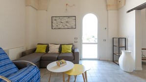 Een woonkamer met een bank, een bijzettafeltje en een boekenkast.