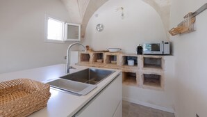 Een keuken met een ingebouwde spoelbak, witte aanrechtbladen, een magnetron en een steenschaar kast.