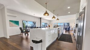 A modern kitchen with a central island, stainless steel appliances, pendant lighting, and a view of the outdoors.