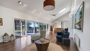 A spacious living room with a large window, a round wooden coffee table, and a blue sofa.