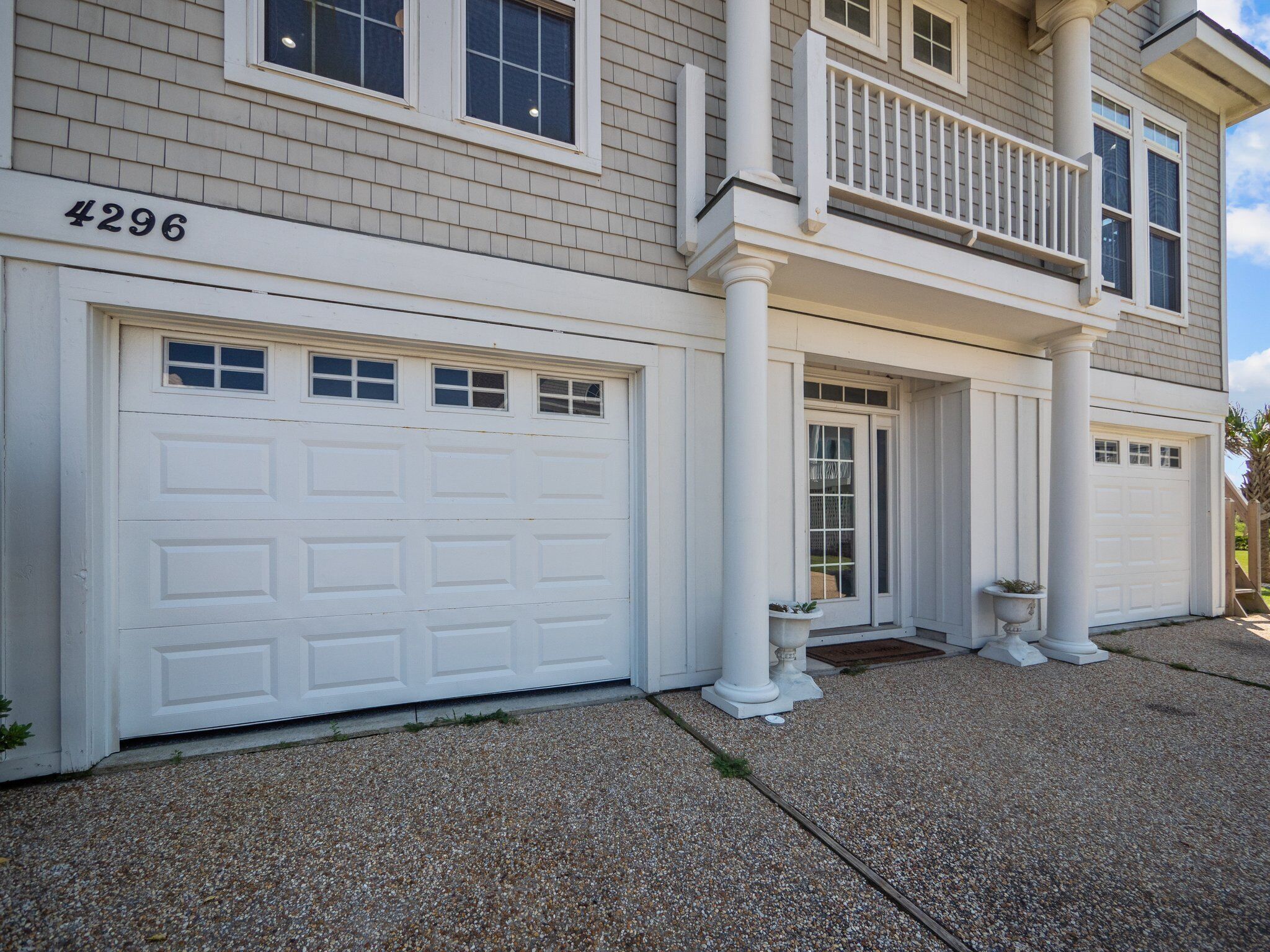 A two-story house with a white garage door, a front porch with columns, and a mailbox.