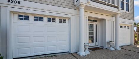 A two-story house with a white garage door, a front porch with columns, and a mailbox.