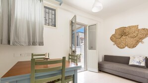 A room with a wooden dining table, green chairs, a grey sofa, and a large woven wall art piece. - 3490 Villetta Boschetto by Barbarhouse (Maruggio)