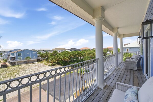 A covered porch with a view of a residential area, a railing, and outdoor furniture.