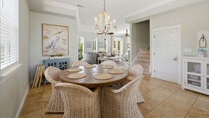 A dining area with a round table, wicker chairs, a chandelier, and a painting of a bird. - Private home across from the beach.  4 bed 3.5 bath sleeps 12 (Navarre)