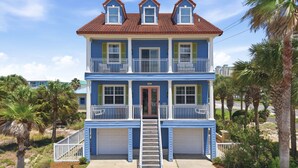 A two-story house with a front porch, a garage, and a staircase leading to the entrance. - Private home across from the beach.  4 bed 3.5 bath sleeps 12 (Navarre)