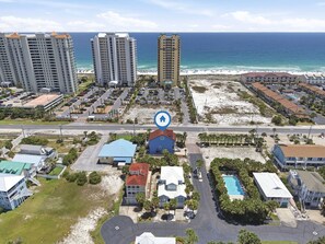 Ein Küstenhotelbereich mit mehreren Gebäuden, einem Parkplatz und einem Strand im Hintergrund.