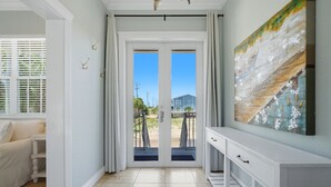 A hallway with a white console table, a door with a view, and a tiled floor. - Private home across from the beach.  4 bed 3.5 bath sleeps 12 (Navarre)