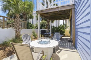 An outdoor patio with a round table, two chairs, a grill, and a covered area.