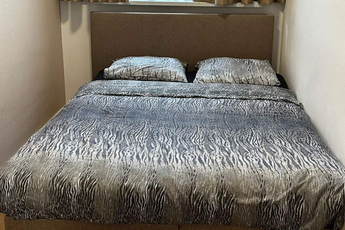 A bedroom with a bed, curtains, and a window.
