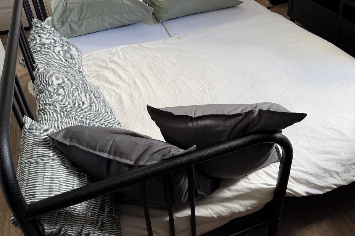 A single bed with a headboard, a television on a stand, and a staircase leading to an upper level.