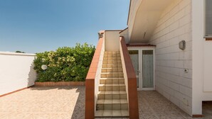 A staircase leading to a door, surrounded by a white wall and a tiled floor.