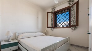 A bedroom with a bed, nightstand, lamp, and window with curtains.