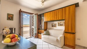 A room with a sofa, a table with fruit, a ceiling fan, and wooden cabinets.