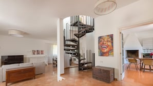 A spacious living area with a spiral staircase, a sofa, a coffee table, and a kitchen visible through an open door. - 3600 Al Giardino Dell`eden by Barbarhouse (Lecce)