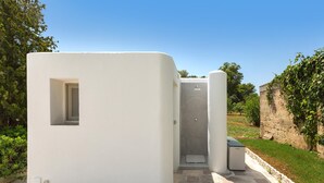 A compact, white, modern structure with a small window and a door, situated in a landscaped area with a stone pathway and greenery. - 3600 Al Giardino Dell`eden by Barbarhouse (Lecce)