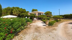 A modern house with a gravel driveway, surrounded by lush greenery and a clear blue sky. - 3600 Al Giardino Dell`eden by Barbarhouse (Lecce)
